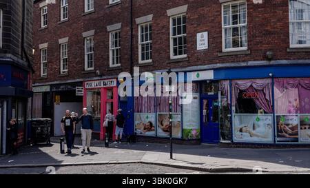 NEWCASTLE, Regno Unito - 13 GIUGNO 2025 - i turisti camminano in Pink Lane, una strada storica di Newcastle upon Tyne, Regno Unito, esplorando negozi e aziende locali Foto Stock