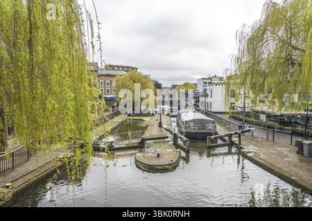 Il canale di Regent scorre attraverso la chiusa della città di camden, con rami di salice piangenti che incorniciano la scena e una barca stretta ormeggiata nella chiusa, catturando l'ess Foto Stock