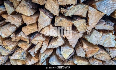 Vista dettagliata dei tronchi divisi impilati in un pelo di legno, mostrando venature di legno grezzo, superfici di taglio e texture rustiche. Foto Stock