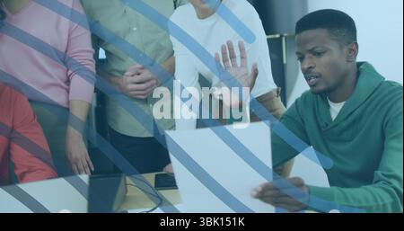 Revisione di un documento, uomo nero con cappuccio verde seduto al tavolo dell'ufficio con laptop, spazio per le copie Foto Stock