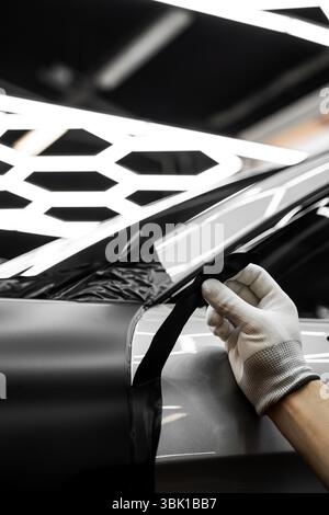L'applicazione di avvolgimento per auto modifica l'aspetto del veicolo. Rivestimento in vinile per auto a pannello intero. L'installazione di un involucro in vinile su larga scala trasforma il wi-fi esterno del veicolo Foto Stock