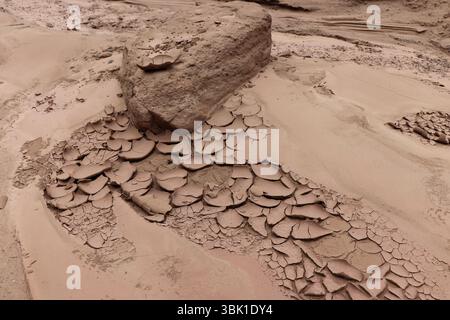 Una roccia solitaria si trova sulla terra incrinata dalla siccità, che mostra l'aridità e gli effetti dell'erosione nel paesaggio di Cañadón del Indio a Fiambalá, Catama Foto Stock