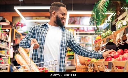 Acquisto della drogheria, Guy afroamericano nel supermercato che sceglie la frutta Foto Stock