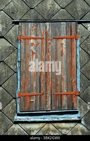Persiane chiuse in legno con vernice che si stacca contro un edificio vecchio, Auvergne, Francia Foto Stock