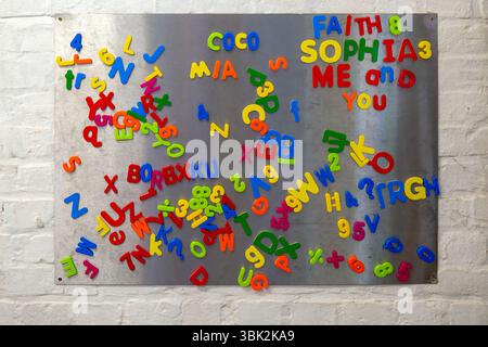 Lettere e numeri magnetici colorati in plastica su scheda di metallo, Regno Unito Foto Stock