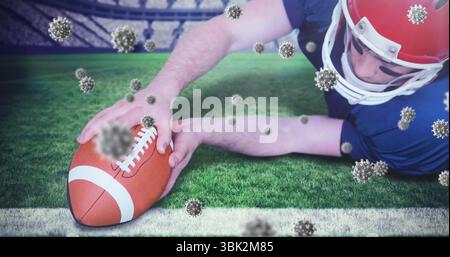 Giocatore di calcio subacqueo con casco rosso, maglia che posiziona palla sulla linea della porta dello stadio, particelle di virus Foto Stock