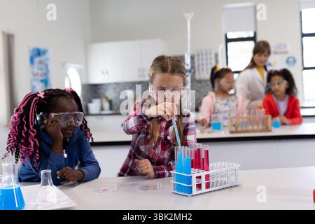Diversi bambini delle scuole che conducono esperimenti scientifici con provette in classe Foto Stock