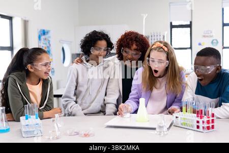 Condurre esperimenti in classe scientifica, diversi studenti che osservano la reazione chimica, a scuola Foto Stock