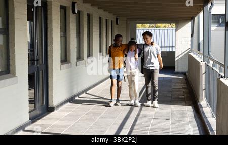 studenti diversi che camminano nei corridoi scolastici, condividendo amicizia e risate Foto Stock