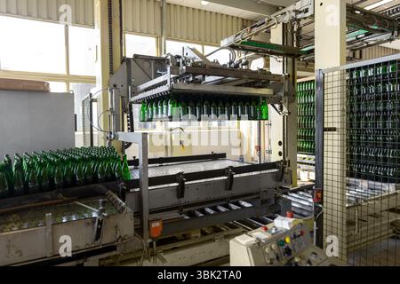 Imbottigliatrice con molte bottiglie in fabbrica Foto Stock