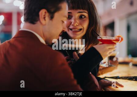 Una coppia felice si diverte con un drink in un accogliente ambiente bar Foto Stock