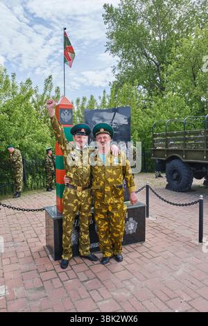 Aromashevo, Russia - 28 maggio 2025: Due veterani in uniforme mimetica si trovano in un memoriale rurale della guardia di frontiera durante la celebrazione del Border Guards Day in R. Foto Stock