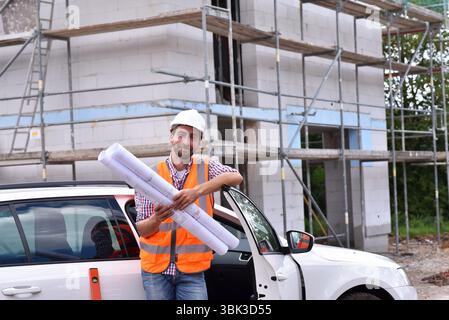 Ritratto sorridente construction manager / architetto sul sito durante la costruzione di una casa - la pianificazione e il controllo in loco Foto Stock