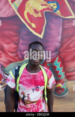 Giovane uomo in piedi di fronte a un murale a Cotonou, Benin Foto Stock