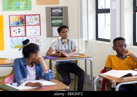 Studenti diversi in classe ascoltando attentamente durante la lezione, coinvolgendo l'insegnante, a scuola Foto Stock