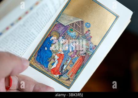 Uomo cattolico che legge un messale illustrato. Natività di Gesù o nascita di Cristo. Adorazione del bambino Gesù da parte dei tre saggi o Magi. Foto Stock