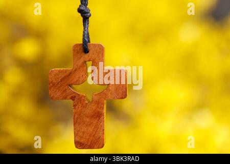 Scopa in fiore in primavera. coss cristiano in legno con Spirito Santo su sfondo giallo. Foto Stock