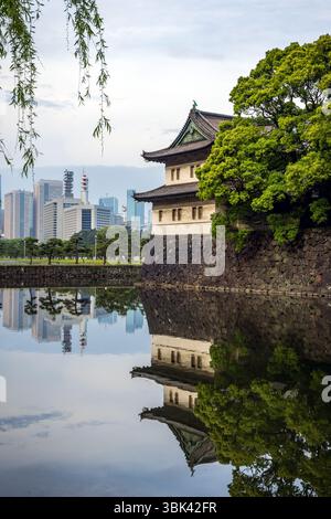 Il fossato di Kikyo-bori intorno al vecchio castello di Edo con la torre di guardia Sakurada Tatsumi Yagura e i moderni grattacieli della città di Tokyo sullo sfondo Foto Stock