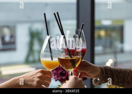 Gli amici celebrano il loro incontro mentre allevano bevande analcoliche colorate a base di succhi sani. L'atmosfera è vivace, piena di gioia e coinvolgente Foto Stock