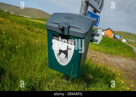 Cestino per i rifiuti dei cani ben contrassegnato in un ambiente rurale delle Shetland, incoraggiando la proprietà responsabile degli animali domestici e spazi pubblici puliti. Foto Stock