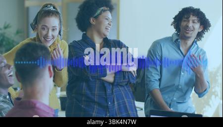 Colleghi che ridono discutono di presentazioni audio intorno alla scrivania in un ufficio moderno, con forme d'onda audio Foto Stock