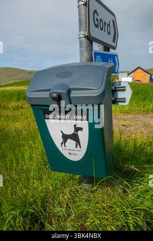 Cestino per i rifiuti dei cani ben contrassegnato in un ambiente rurale delle Shetland, incoraggiando la proprietà responsabile degli animali domestici e spazi pubblici puliti. Foto Stock