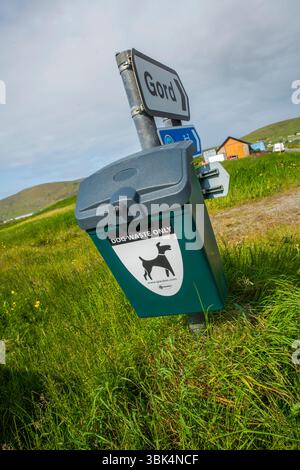 Cestino per i rifiuti dei cani ben contrassegnato in un ambiente rurale delle Shetland, incoraggiando la proprietà responsabile degli animali domestici e spazi pubblici puliti. Foto Stock