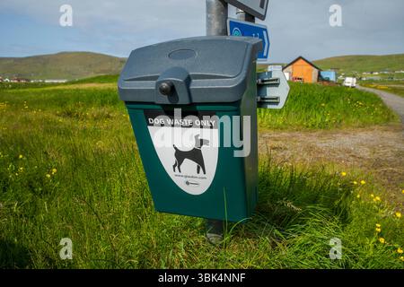 Cestino per i rifiuti dei cani ben contrassegnato in un ambiente rurale delle Shetland, incoraggiando la proprietà responsabile degli animali domestici e spazi pubblici puliti. Foto Stock
