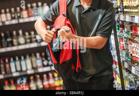 Colonia, Germania. 18 giugno 2025. ILLUSTRAZIONE - Un uomo mette una bottiglia di bevanda alcolica nello zaino in un supermercato. Viene pubblicato uno studio HI sulle discrepanze di taccheggio e inventario. Crediti: Oliver Berg/dpa/Alamy Live News Foto Stock