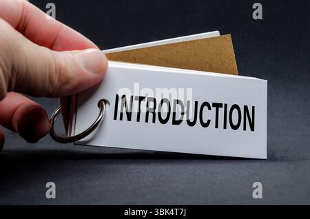 Capovolgere a mano una pagina del notebook con un'etichetta DI INTRODUZIONE visibile Foto Stock