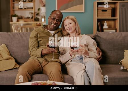 Coppia multietnica senior seduta insieme godendosi una serata romantica all'interno Foto Stock