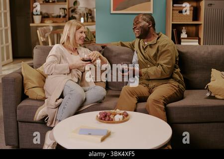 Coppia senior diversificata che si gode una conversazione romantica all'interno Foto Stock