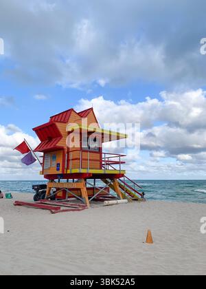 Una vivace e moderna baracca bagnino sorge sulle sabbie bianche di Miami Beach, con l'oceano turchese e il cielo spettacolare che creano una scena costiera Foto Stock