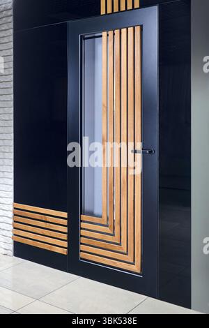 Interni dal design moderno. Porta in alluminio con spranghe in legno verticali e orizzontali e parti in vetro in profili in alluminio. Foto Stock