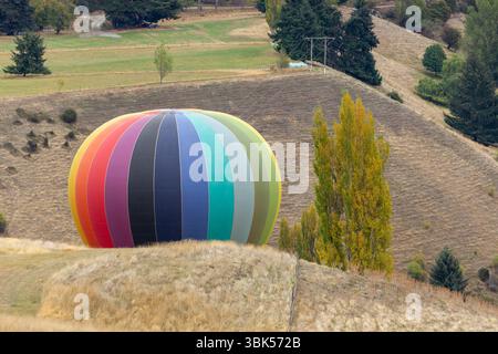 Un atterraggio in mongolfiera che scompare tra i campi ondulati vicino a Queenstown, Otago, nuova Zelanda Foto Stock