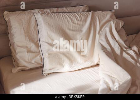 Cuscini morbidi e lenzuola deformate su un letto confortevole. Foto Stock