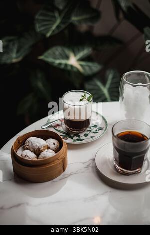 Caffè e nocciole su tavolo in marmo con sfondo verde Foto Stock