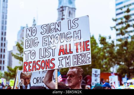 L'uomo ha il segno "No sign is enough to list all the reasons i'm here" (nessun segno è abbastanza grande da elencare tutte le ragioni per cui sono qui) durante il rally "No Kings" a Philadelphia, Pennsylvania, il 14 giugno 2025 Foto Stock