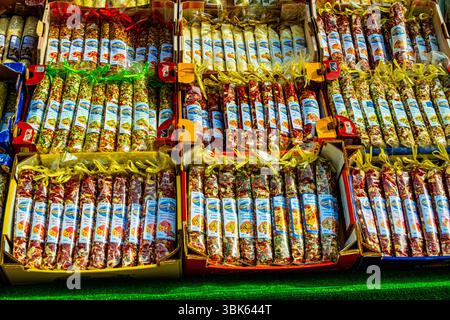 Venezia, Italia – 12 giugno 2025: Torrone e dolciumi italiani confezionati assortiti esposti in vendita presso un tradizionale bancone del mercato. Foto Stock