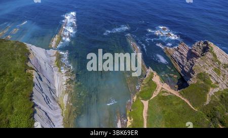 Vista aerea mozzafiato delle uniche formazioni rocciose flysch lungo la costa di zumaia, nei Paesi baschi, che mostrano lo straordinario contrasto di tur Foto Stock