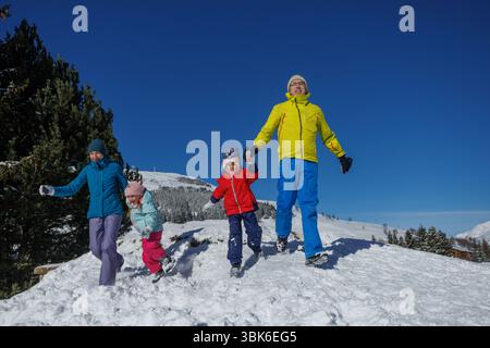 Famiglia felice che corre in discesa e che si diverte durante le vacanze invernali Foto Stock
