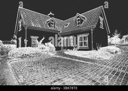La casa a due piani e' in piedi su sfondo scuro con porta d'ingresso, arbusti, vialetto di mattoni Foto Stock