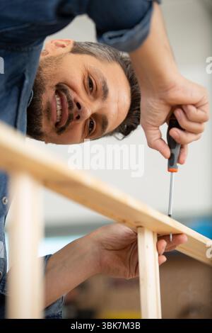 uomo felice che assembla mobili a casa sul pavimento Foto Stock