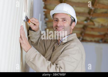 Lavoratore edile con lunga cazzuola intonacatura di una parete Foto Stock