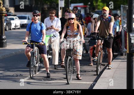 I ciclisti si spostano al mattino lungo il Victoria Embankment vicino al Westminster Bridge nel centro di Londra. Le temperature potrebbero raggiungere i 33C questo fine settimana, mentre parti del Regno Unito si crogiolano in un'ondata di caldo. Data foto: Giovedì 19 giugno 2025. Foto Stock