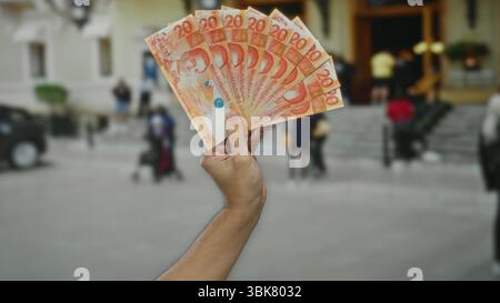 Uomo che detiene più banconote da 20 pesos filippine all'aperto in un ambiente urbano. Foto Stock