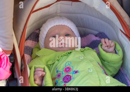 bellissimo bambino autunnale sdraiato in un passeggino vestito con calore Foto Stock