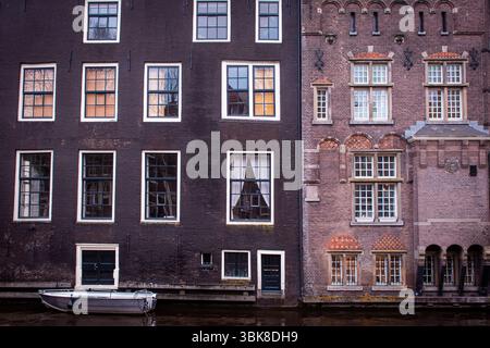 Un pittoresco canale di Amsterdam, fiancheggiato da tradizionali edifici olandesi caratterizzati da alte, strette facciate e grandi finestre. Foto Stock