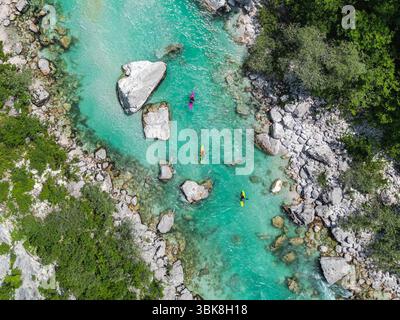 Vista aerea con drone di tre kayak sul fiume turchese Soča. Idilliaca vista dall'alto di acque cristalline, rocce e alberi. Kayak in Slovenia Foto Stock