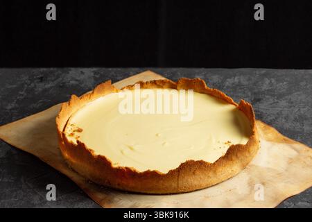 Cheesecake classica fatta in casa su sfondo scuro. Preparare una deliziosa torta a casa Foto Stock